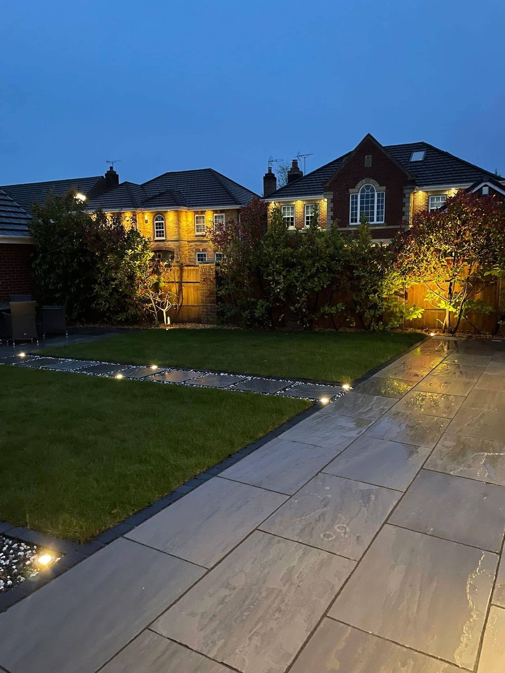 Garden with in-ground and wall lighting at dusk