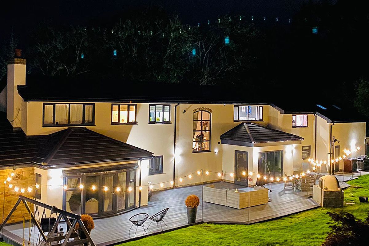 House and garden lit up at night with festoon and wall lights