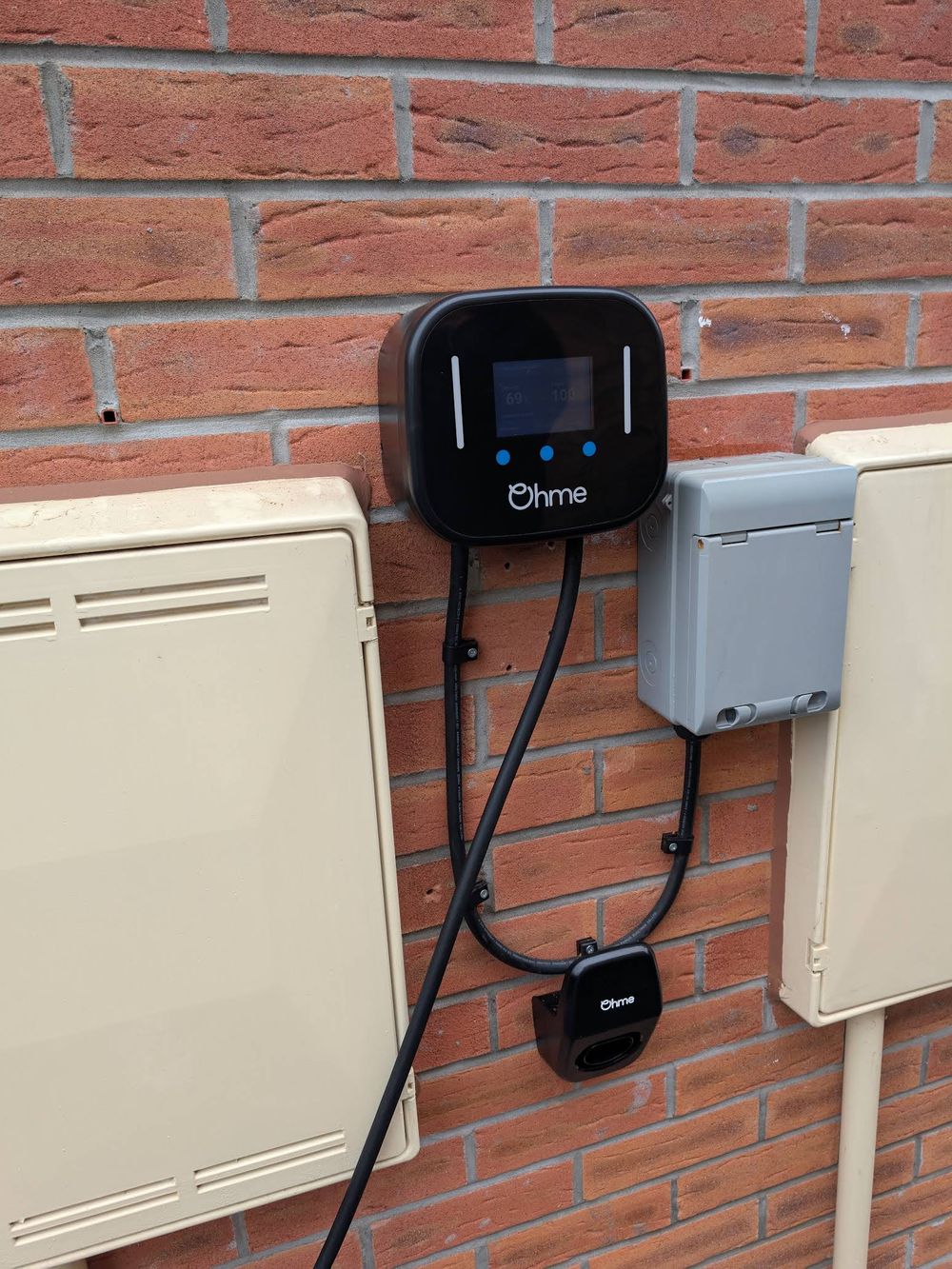 Ohme home EV charger on a brick wall